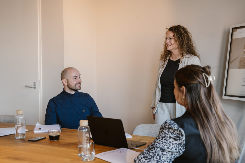 Twee vrouwen en man in overleg in een vergaderruimte